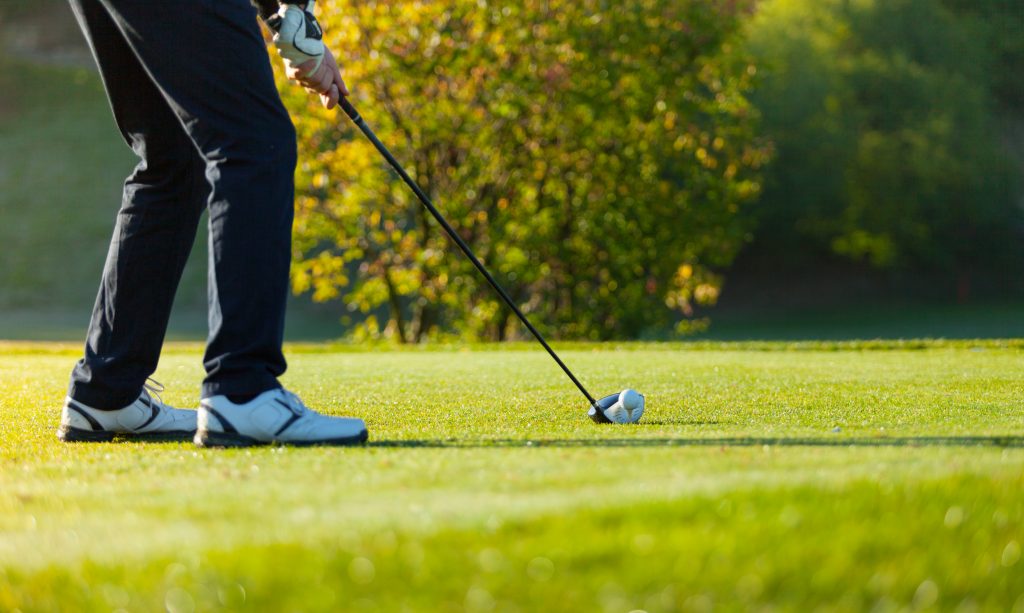 Close-up of man playing golf on green golf course. Hitting golf ball